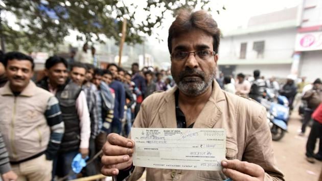 A man showing his salary cheque that has not been accepted by the bank of India due to the shortage of new currency in their bank at Jheel chowk branch, in New Delhi,on November 30, 2016.(HT PHOTO)