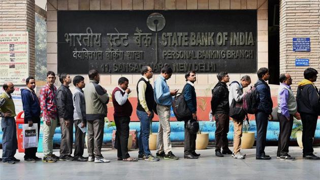 People stand in line outside a bank to withdraw cash in New Delhi.(PTI)