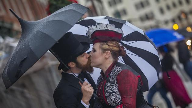 A couple kiss under their umbrellas at Dickens on The Strand in Galveston, Texas, on Saturday. Due to the inclement weather, organisers had to waive admission fees and later announce that the festival would be held again a week later. (AP)