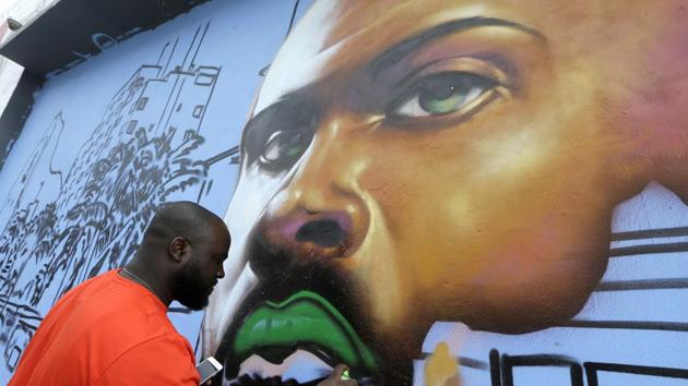 An artist works on a mural in the Wynwood Art District in Miami on , Friday, as part of the 15th Art Basel festival. (AP)