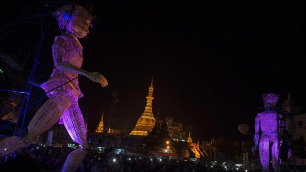 People watch two giant wicker puppets from the French cultural group L’Homme Debout parade near Sule Pagoda, during the Mingalabar Festival in central Yangon on Saturday. (AFP)
