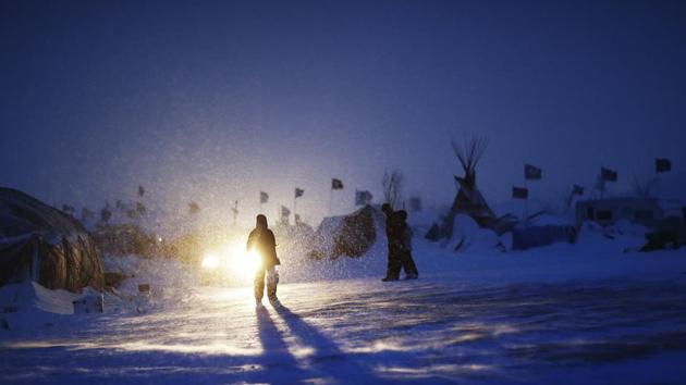 People walk through a snow storm at the Oceti Sakowin camp where demonstrators have gathered to protest the Dakota Access oil pipeline in Cannon Ball, North Dakota. Those in the camp have weathered heavy snow, icy winds and frigid temperatures. (AP) People walk through a snow storm at the Oceti Sakowin camp where demonstrators have gathered to protest the Dakota Access oil pipeline in Cannon Ball, North Dakota. Those in the camp have weathered heavy snow, icy winds and frigid temperatures. (AP)