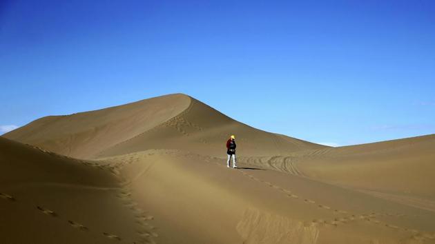 An Iranian woman walks on the sands. The increase in tourists to the desert has stimulated economic growth in the area. (AP)