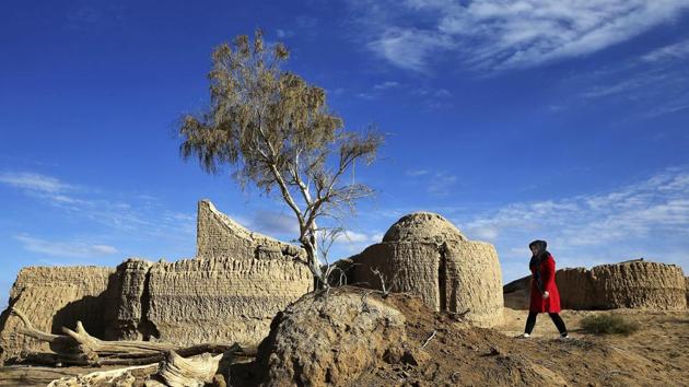 An Iranian tourist walks alongside the remains of old buildings in the Mesr desert. (AP)