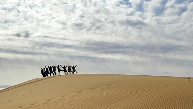 Iranian youths form a dance line in the desert. There is also a town of the same name close by. (AP)