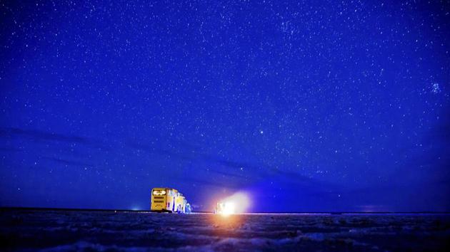 A tourist bus parks in the Khour salt lake as Iranians warm themselves around a fire, while watching stars. Other attractions include watching the moonrise, star gazing, the dunes, the camels, the traditional houses and listening to the silence of the desert. (AP)