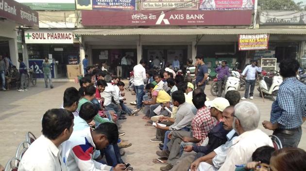 People wait outside an Axis Bank branch in Noida. The bank has suspended 19 employees across India including 6 in Delhi’s Kashmere Gate branch over alleged involvement in illegal practices, post demonetisation.(Mohd Zakir / HT File Photo)