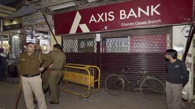 Police men guard outside an Axis Bank branch during a raid by Income Tax officials in the Chandni Chowk in New Delhi on Friday. The officials have found several fake accounts in the bank.(PTI Photo)