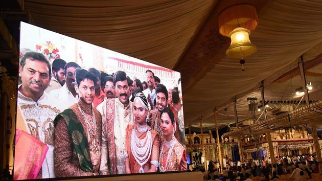 Mining baron G Janardhan Reddy is seen on a big screen as he poses with his daughter Bramhani and son-in-law, Rajeev Reddy during their wedding at the Bangalore Palace Grounds in Bangalore. (AFP File Photo) Mining baron G Janardhan Reddy is seen on a big screen as he poses with his daughter Bramhani and son-in-law, Rajeev Reddy during their wedding at the Bangalore Palace Grounds in Bangalore. (AFP File Photo)
