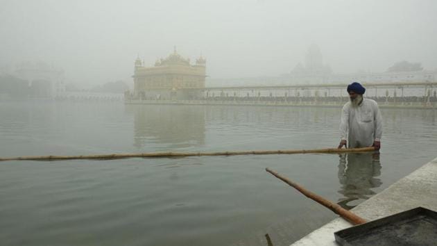 A worker cleans the holy sarovar (pond) at the Golden Temple in Amritsar on a foggy morning. (Gurpreet Singh/HT)