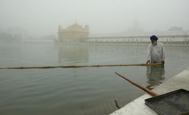 A worker cleans the holy sarovar (pond) at the Golden Temple in Amritsar on a foggy morning. (Gurpreet Singh/HT)