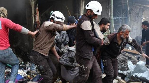 Syrian men and Civil Defence volunteers, also known as the White Helmets, evacuate a victim from a building following an air strike on the village of Maaret al-Numan.(AFP Photo)