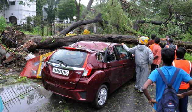 Rescue workers trying to remove an uprooted tree from a vehicle in Chennai on Monday. (Vanne Srinivasulu / Hindustan Times) Rescue workers trying to remove an uprooted tree from a vehicle in Chennai on Monday. (Vanne Srinivasulu / Hindustan Times)