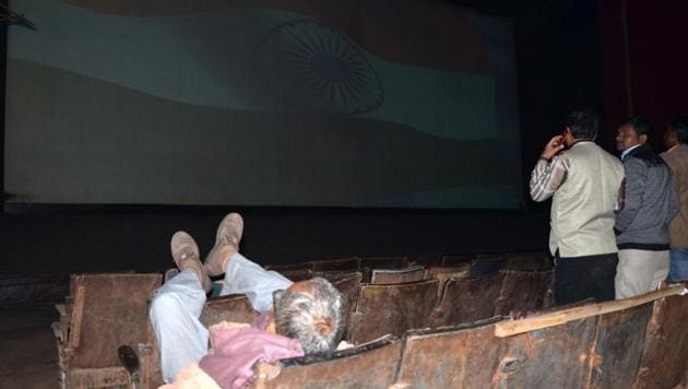 An old man sleeps with his feet up as the national anthem is played at Prasad Cinema hall in Bareilly.