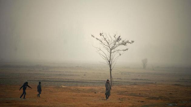 Kashmiri boys walk through a field on a cold and foggy day in Srinagar on December 9, 2016. (AFP)