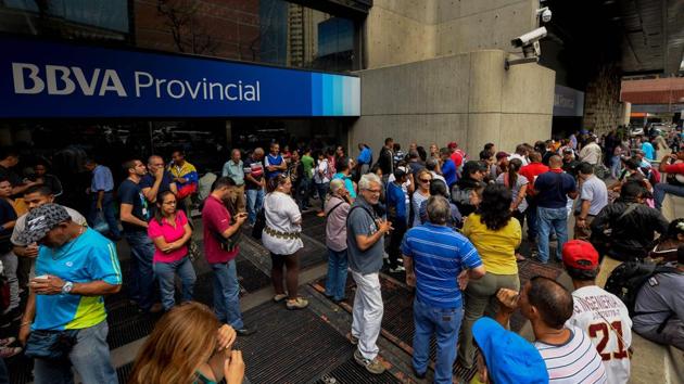 People queue outside a bank in Caracas in an attempt to deposit money, on December 13, 2016. Venezuelan President Nicolas Maduro signed an emergency decree removing Venezuela's largest bank note, the 100 bolivar bill, from circulation because of what he called a Washington-sponsored plot against his country's troubled economy. (AFP Photo) People queue outside a bank in Caracas in an attempt to deposit money, on December 13, 2016. Venezuelan President Nicolas Maduro signed an emergency decree removing Venezuela's largest bank note, the 100 bolivar bill, from circulation because of what he called a Washington-sponsored plot against his country's troubled economy. (AFP Photo)