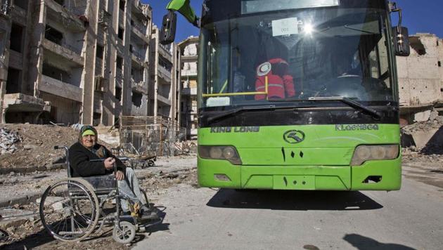 An elderly Syrian woman in a wheelchair waits next to a bus during an evacuation operation of rebel fighters and their families from rebel-held neighbourhoods in the embattled city of Aleppo on Thursday.(AFP)