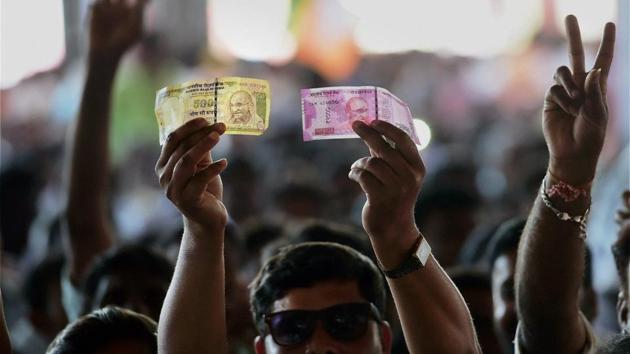 A BJP supporter shows a demonetised Rs 500 currency note and a new Rs 2000 currency note in Bengaluru on Sunday.(PTI)