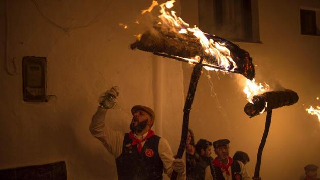 Men drink anisette and hold burning rondeles during the procession to mark the feast of Saint Lucia. (AFP) Men drink anisette and hold burning rondeles during the procession to mark the feast of Saint Lucia. (AFP)