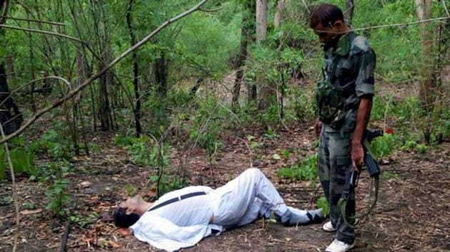 A security personnel stands near the body of one of the victims of Maoist attack in a densely forested area in Bastar, about 345 kilometers (215 miles) south of Raipur, Chhattisgarh.(AP File Photo)
