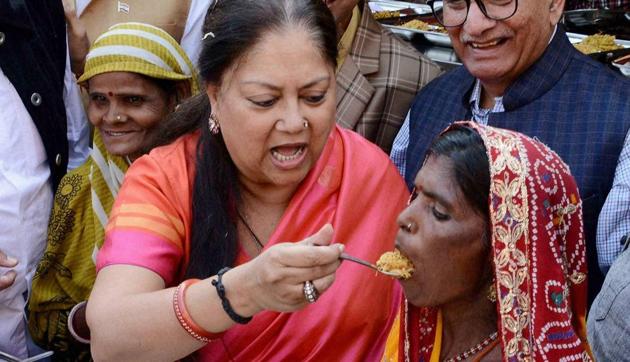 Rajasthan chief minister Vasundhara Raje shares food with a woman during the launch of 'Annapurana Rasoi Yojana , in Jaipur on Thursday.(PTI)