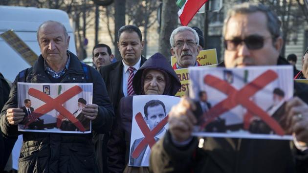 Syrian and Iranian migrants hold pictures of Syrian President Bashar Assad and supreme leader Ayatollah Ali Khamenei during a gathering to protest against the war in Aleppo outside the Iranian embassy in Paris..  (Michel Euler/AP Photo) 