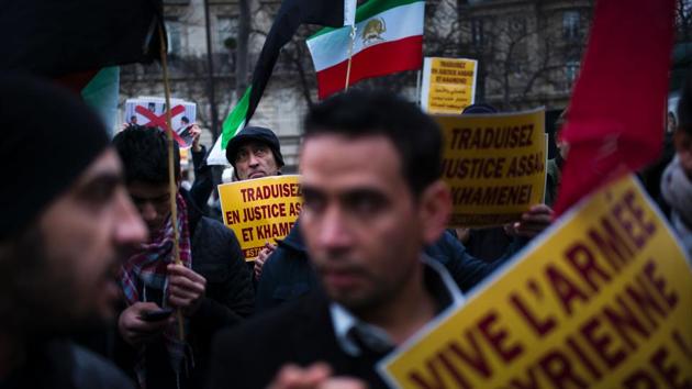 People hold signs reading "Bring Bashar al-Assad and Ali Khamenei to justice" and "long live Free Syrian Army" during a protest of Syrian demonstrators near the Iranian embassy against Iranian involvement in the siege of Aleppo. (Martin/AFP Photo) 