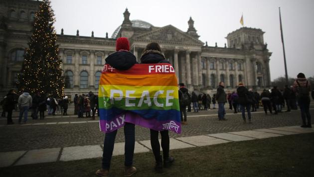 Two women covered with a peace flag attend a demonstration against the ongoing war in Syria and the humanitarian crisis in besieged Aleppo in front of the Reichstag Parliament building in Berlin. (Markus Schreiber/AP Photo) 