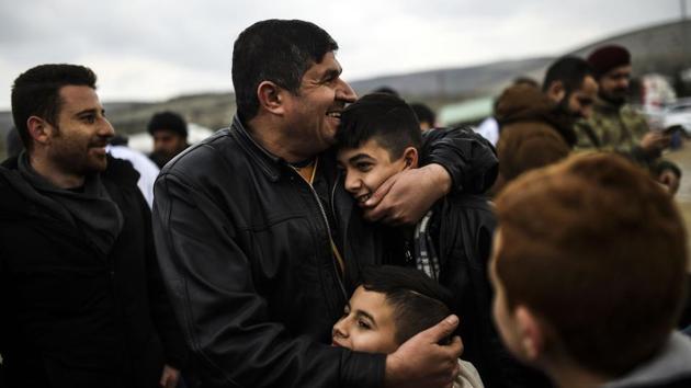 Syrian father Ali embraces his children upon their arrival from the Syrian city of Idlib to the Turkish crossing gate of Cilvegozu in Reyhanli in Hatay near the Syrian border. (Bulent Kilic/AFP Photo) 