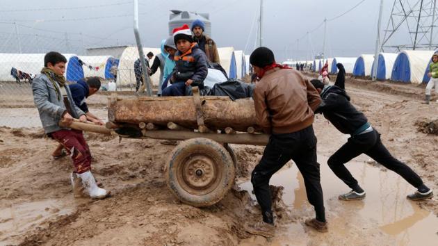 Displaced Iraqis who fled the Islamic State stronghold of Mosul, push a cart through mud following heavy rain at the Khazer camp, Iraq. (Ammar Awad / REUTERS)