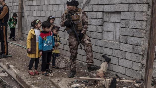 Iraqi children look at the body of a half-buried Islamic State militant while talking to an Iraqi soldier in the al-Barid district in Mosul, Iraq. In a part of Mosul that had been reclaimed from the Islamic State group (IS) days ago, Iraqi special forces were attacked on Sunday by drones operated by IS fighters inside the city. (Manu Brabo / AP)