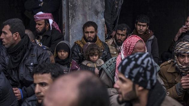 An Iraqi man and his sons wait with other displaced Iraqis to be transferred to camps by the Iraqi Army in the village of Bartella, near Mosul. Thousands of people try to leave the city each day and the number of displaced now tops 120,000, according to the Iraqi ministry of migration and displacement. (Manu Brabo / AP)