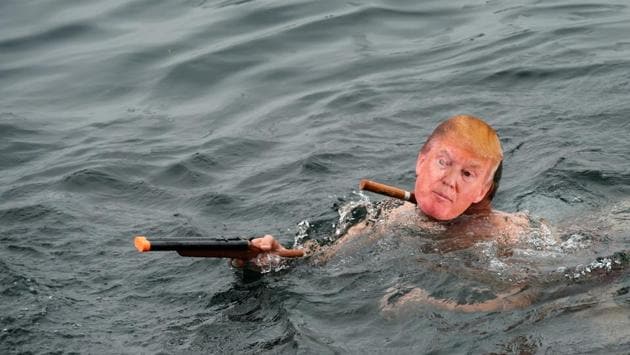 A man wearing a mask of US President elect Donald Trump and a toy gun swims in lake Geneva. (Fabrice Coffrini/AFP) A man wearing a mask of US President elect Donald Trump and a toy gun swims in lake Geneva. (Fabrice Coffrini/AFP)
