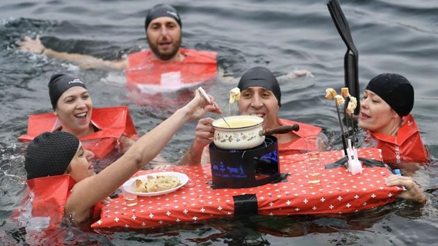 People eat a cheese fondue as they swim during the 78th "Coupe de Noel". (Fabrice Coffrini/AFP) People eat a cheese fondue as they swim during the 78th "Coupe de Noel". (Fabrice Coffrini/AFP)