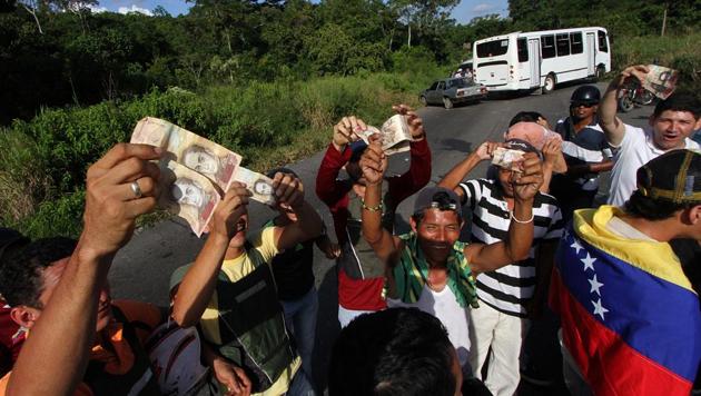 People hold up 100-Bolivar notes during a protest over lack of cash as the new bank notes have not yet appeared, in San Cristobal in Venezuela's Tachira state, on December 16, 2016. (AFP) People hold up 100-Bolivar notes during a protest over lack of cash as the new bank notes have not yet appeared, in San Cristobal in Venezuela's Tachira state, on December 16, 2016. (AFP)