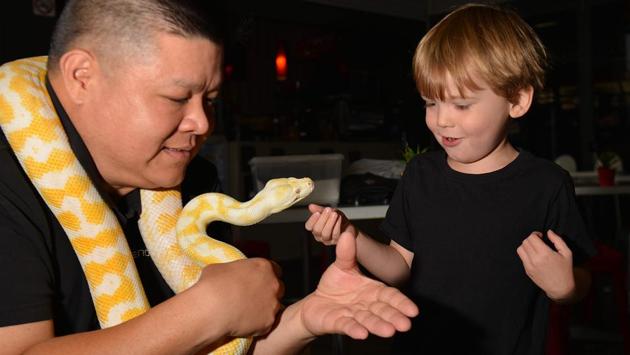 Reptile breeder Ernie Chan (left) shows off ‘Malfoy’, an albino Darwin carpet python, to 4-year-old Charlie Kallekleiv at a pet store in Sydney. (Peter Parks/AFP)