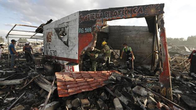 Firefighters and rescue workers remove debris from the scorched ground of Mexico's best-known fireworks market after an explosion ripped through it. (Eduardo Verdugo/AP)