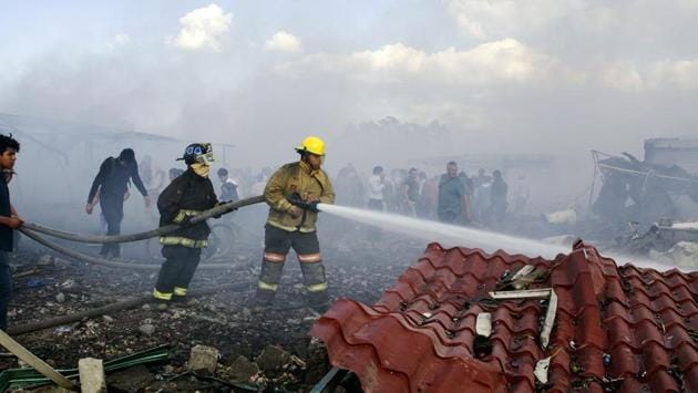 Fire fighters put out smoldering embers amid the debris left by a huge blast that occurred in a fireworks market in Mexico City. (Israel Gutiérrez/AFP)