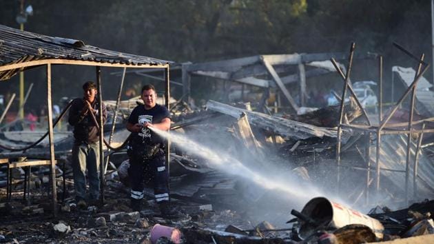 Rescue workers put out smoldering embers after the blast. (Ronaldo Schemidt/AFP)
