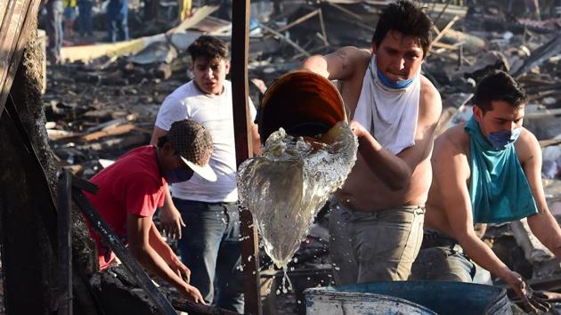 Locals join the rescue workers to douse the embers amid the debris after the blast. (Ronaldo Schemidt/AFP)