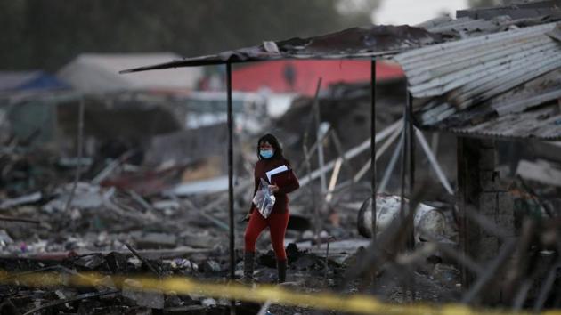 A woman walks amid the remains of houses destroyed in an explosion at the San Pablito fireworks market outside the Mexican capital on Tuesday, in Tultepec, Mexico. (Edgard Garrido/REUTERS)