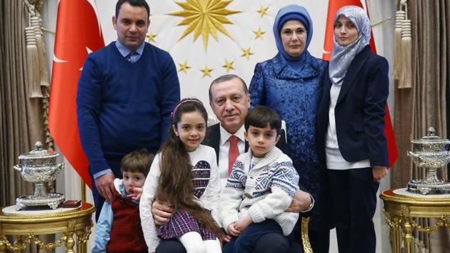 A handout picture taken and released by the Turkish Presidential press office on December 21, 2016 shows Turkey's President Recep Tayyip Erdogan (C) and his wife Emine Erdogan (2nd R) posing with the seven-year-old Bana al-Abed (3rd L), who tweeted from Aleppo on the attacks, and her family, at the Presidential Complex in Ankara.(AFP)