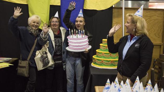 Michele Frymen, from left, Christy Anderson and Jacob Anderson, all from Columbus, hold up a birthday cake and wave as they get their picture taken during some festivities in the food court as part of the 60th birthday celebration for Colo. (AP Photo)