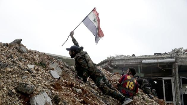 A Syrian army soldier places the national flag during a battle with rebel fighters at the Ramouseh front line, east of Aleppo.(AP Photo)