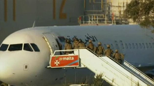 An Afriqiyah Airways plane sits on the tarmac at Malta's Luqa International airport as military personnel approach it. After hours of tense negotiations, Libyans who hijacked the plane from Libya to Malta and threatened to blow it up surrendered peacefully, allowing the passengers and crew to leave the plane before walking out themselves with the last of the crew. (AP Photo)