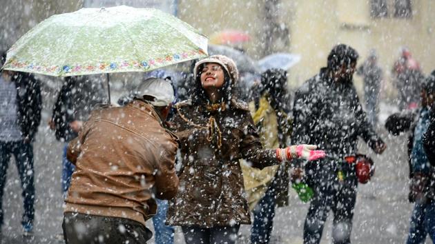 People enjoying the first snowfall of the season at Ridge, in Shimla, on Sunday. (Deepak Sansta/HT Photo)