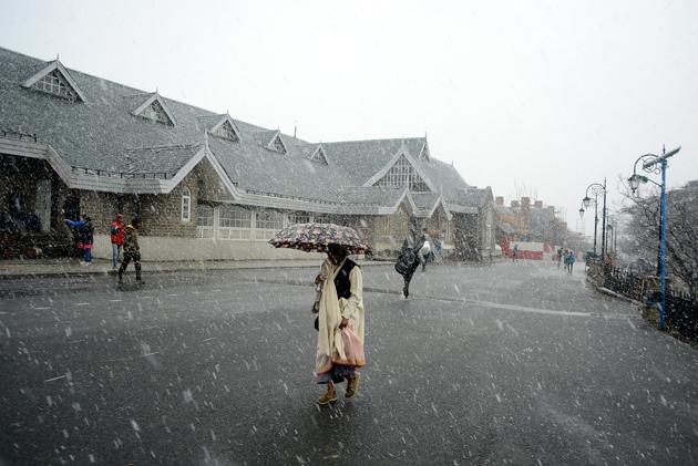 A woman walking with umbrella during the season’s first snowfall on Christmas after 24 years at Ridge in Shimla on Sunday. (Deepak Sansta/HT Photo)