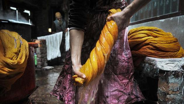 A worker squeezes out excess water after dyeing the threads. Kashmiris have been dyeing fabric and threads manually for around two centuries. (Waseem Andrabi/HT Photo)