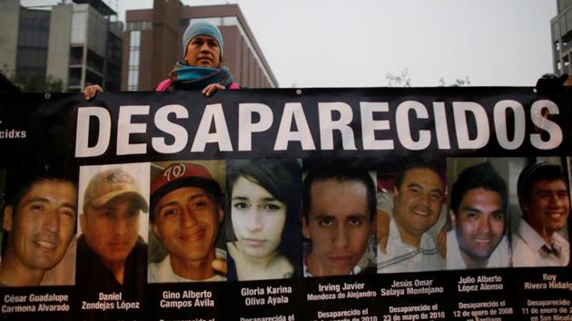 A demonstrator holds a banner with images of her relative and others, who they say went missing or were killed, during a demonstration demanding justice for the victims of violence in Monterrey, Nuevo Leon state, Mexico on December 10, 2016. A sign reading "Disappeared".(Reuters file photo)