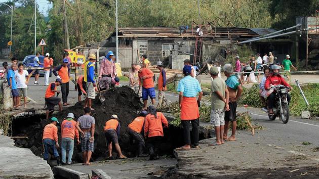 Workers inspect a road damaged that caved in after Typhoon Nock-Ten hit Tabaco, in Albay province. (Charism Sayat/AFP)